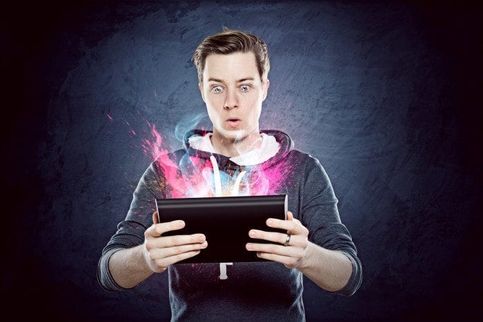 A young man looking astounding by what's going on in his tablet.