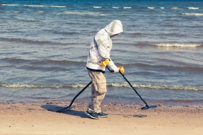 a man is using a metal detector at the beach