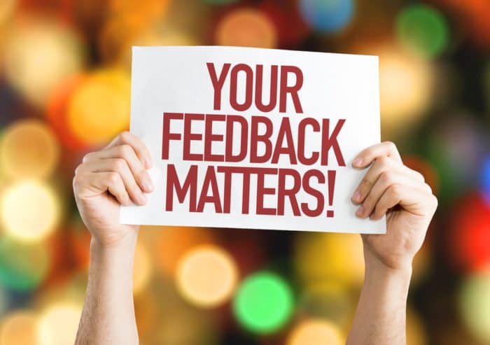 a person holding a piece of paper which says "your feedback matters!".