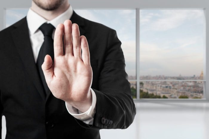 a man in suit raising his hand projecting a "no gesture.