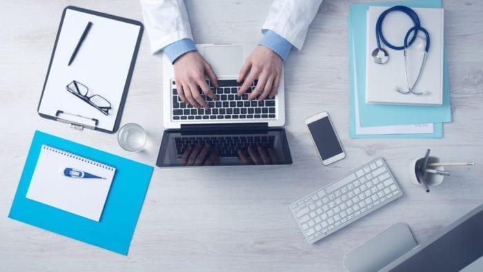Hands typing on a laptop with, doctor products on the desk. important to understand doctors to create their website.