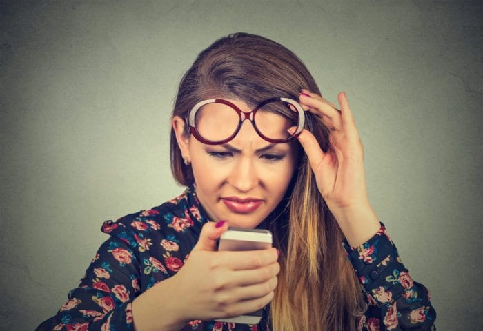 Young woman confusingly looking at her phone, to show to make it easy for patients to look at a medical website.
