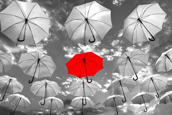 How Optometrists Can Put Their Online Presence In Focus 2 1 Red Umbrella In The Middle Of Many Grey Umbrellas, Standing Out From The Rest. Showing Importance Of Standing Out Online.