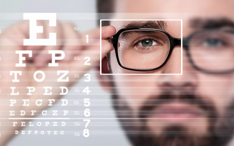 Guy holding glasses with focus on right eye