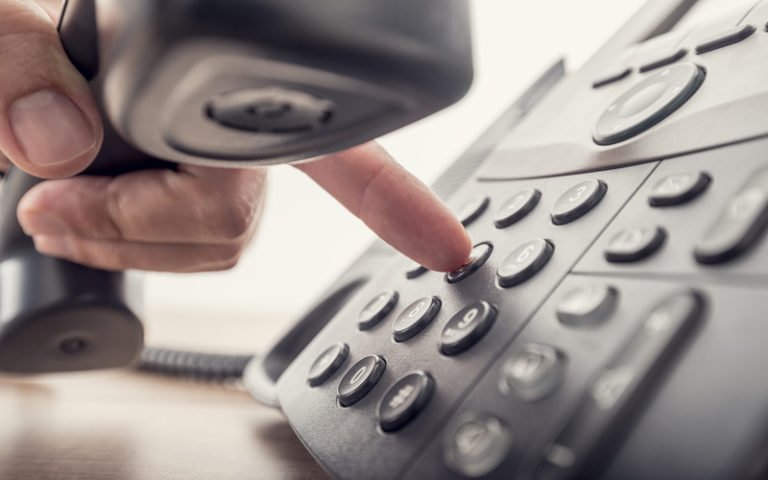 Person holding a telephone receiver and dialing a number