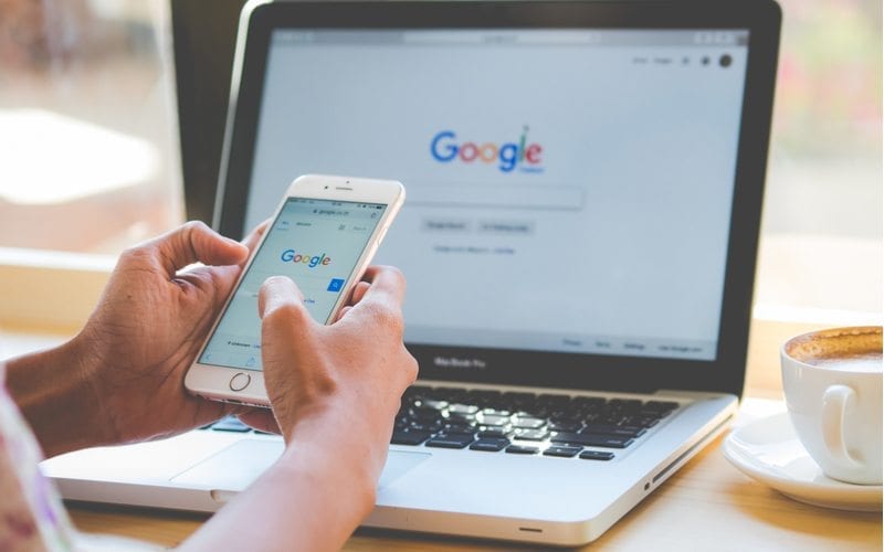 Image of professional holding their mobile device in front of their laptop submitting their medical website design to google sitemap