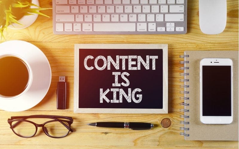 Chalkboard written CONTENT IS KING on wooden desk with flare effect