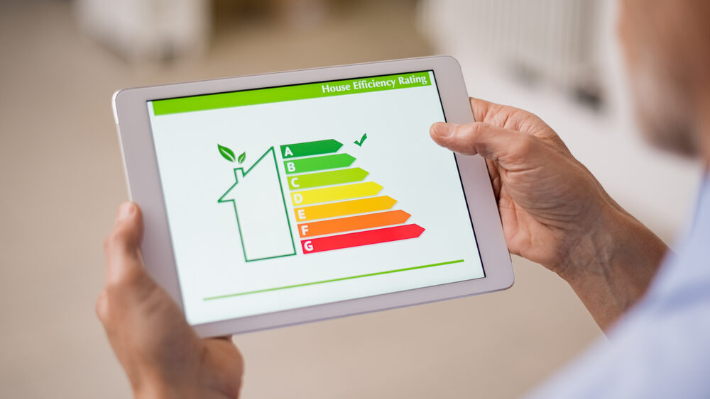Hand holding digital tablet and looking at house efficiency rating. Detail of house efficiency rating on digital tablet screen. Concept of ecological and bio energetic house. Energy class.