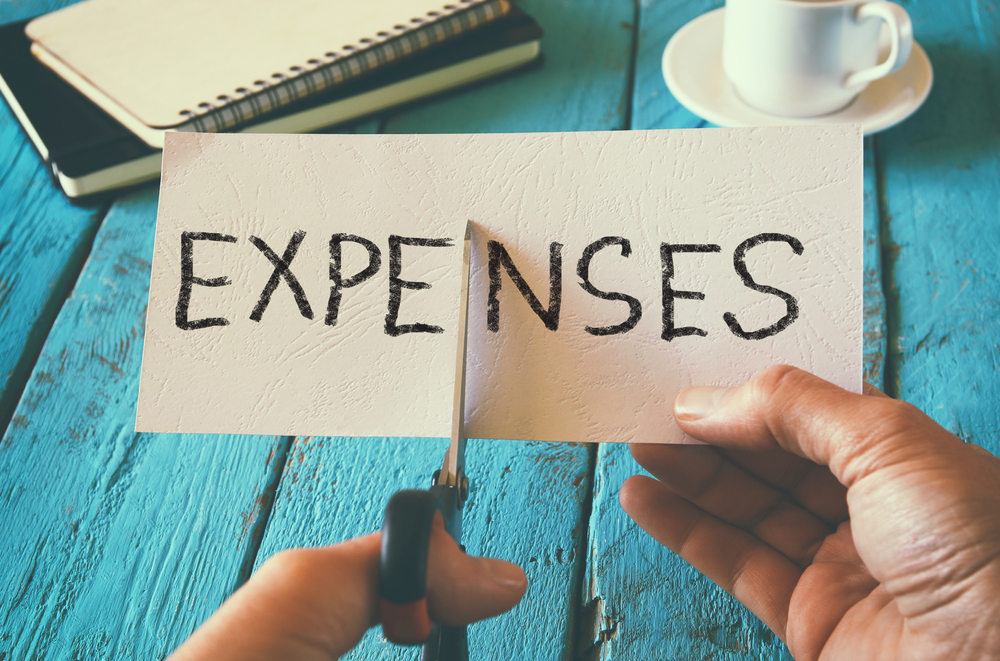 Cutting a paper that says expenses on it